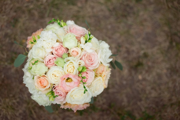 Draufsicht auf einen schönen zarten Hochzeitsstrauß von cremefarbenen Rosen und Eustoma