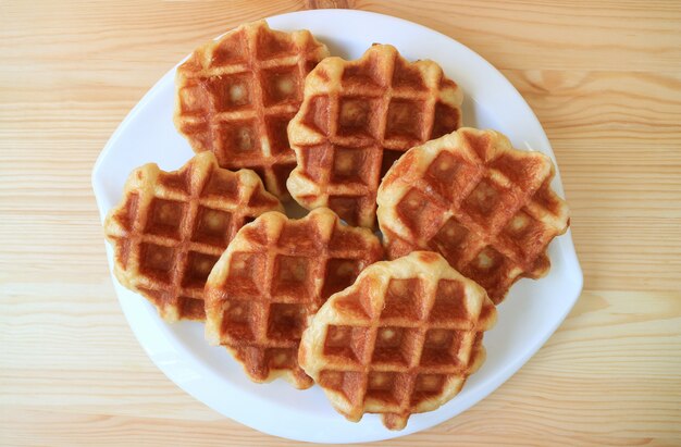 Draufsicht auf einen Teller mit belgischen Waffeln auf Holztisch