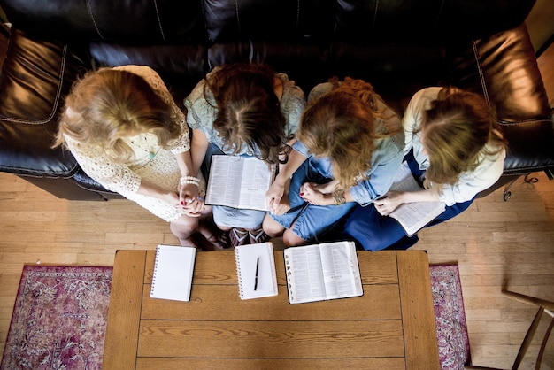 Draufsicht auf Frauen, die Händchen haltend sitzen und in der Bibel lesen