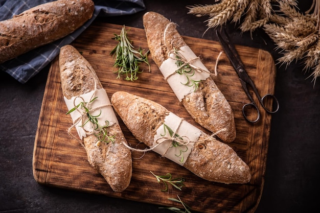 Draufsicht auf frisch gebackenes Gebäckbrot auf einem alten Holzbrett mit dunklem Hintergrund