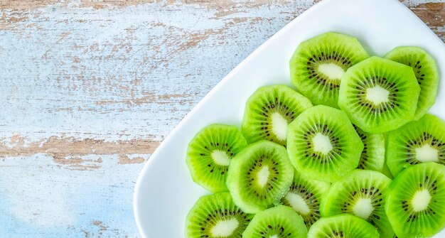 Draufsicht auf frisch grün geschnittene Kiwis in der Platte auf altem Holzhintergrund