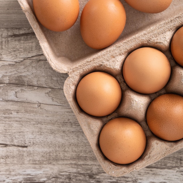 Draufsicht auf frische braune Hühnereier in einem Kraftpapier-Eierkarton auf Holztischhintergrund