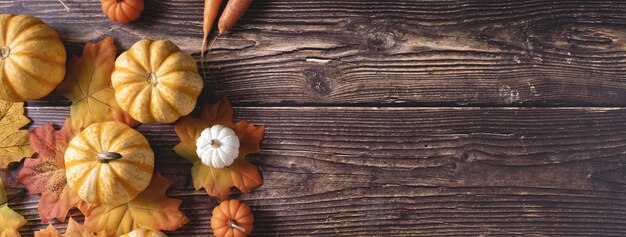 Draufsicht auf frische Kürbisse und Herbstblätter auf einer Holzoberfläche