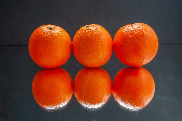 Draufsicht auf frische Orangen, die nebeneinander auf schwarzem Hintergrund mit freiem Platz stehen