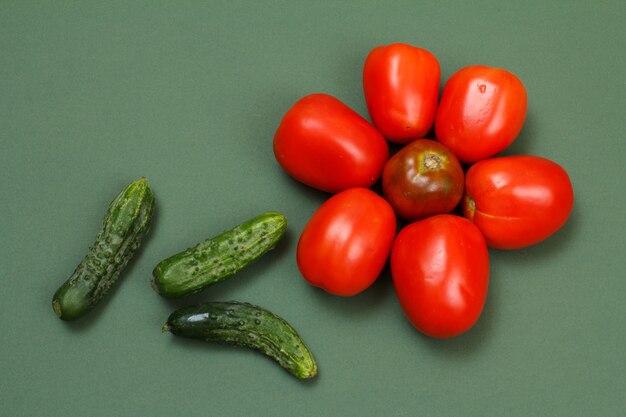 Draufsicht auf frische Tomaten und Gurken auf grünem Hintergrund. Gemüse auf Küchentisch. Ansicht von oben.