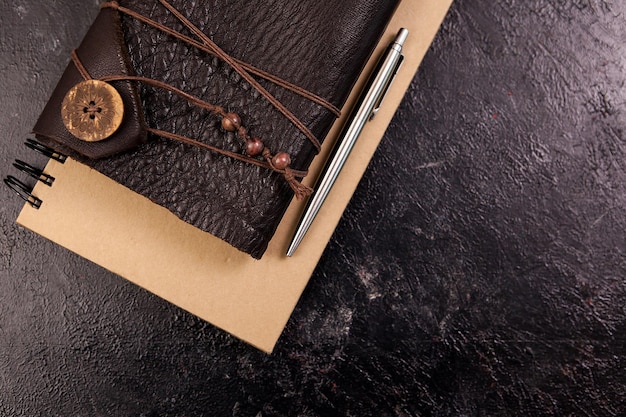 Draufsicht auf gealtertes Retro-Notizbuch mit Ledereinband auf dunklem Holzhintergrund