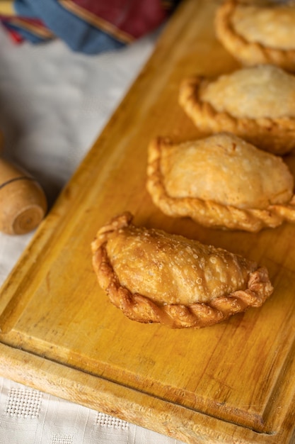 Draufsicht auf gebratene argentinische Empanadas auf einem Holzbrett