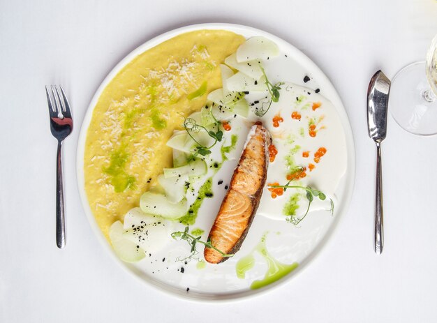 Draufsicht auf gebratenen Lachs mit Kartoffelpüree und rotem Kaviar auf einem weißen Teller