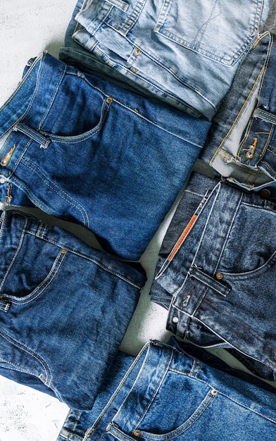 Draufsicht auf gefaltete Jeans, blaue Jeans auf einem Jeansstapel. Draufsicht auf verschiedene Jeansstoffe auf Weiß