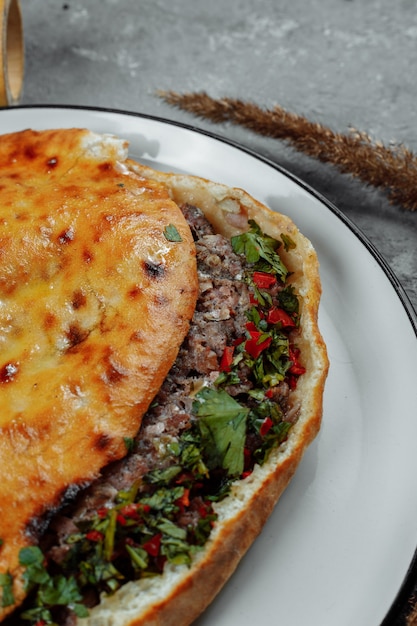 Draufsicht auf georgische Khachapuri mit Lamm und Chilischoten auf dem Holztisch.