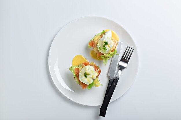 Draufsicht auf geröstete Brötchen mit Speck, Salat und pochiertem Ei