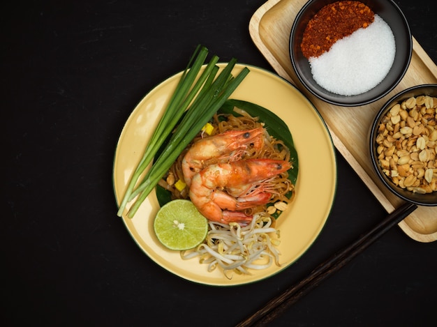 Draufsicht auf gerührte thailändische Nudeln mit Garnelen, die mit Limette, Sprossen und Schnittlauch, Pad Thai, thailändischem Essen dienen