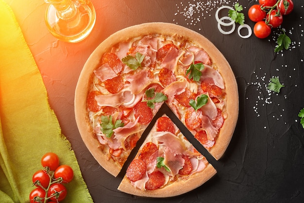 Draufsicht auf geschnittene Pizza mit Salami-Speck und Prosciutto