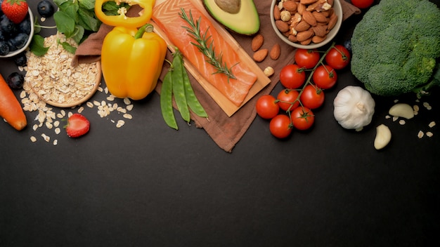 Draufsicht auf gesundes Essen sauberes Auswahlsortiment mit Lachs, Obst, Gemüse, Samen und Kopienraum auf schwarzem Tisch