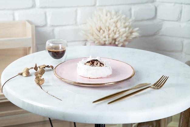 Draufsicht auf gesundes veganes Dessert anna pavlova auf weißem Marmortisch mit Kaffee- und Essensgeschirr. Kopieren Sie Platz für Design. Frisches veganes rohes Dessert. Gesundes Essen. Baiser süßer Kuchen