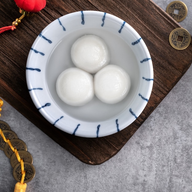 Draufsicht auf große tangyuan yuanxiao (klebrige Reisknödelbällchen) für das Festessen des neuen Mondjahres, Wörter auf der goldenen Münze bedeuten den Dynastienamen, den sie gemacht hat.