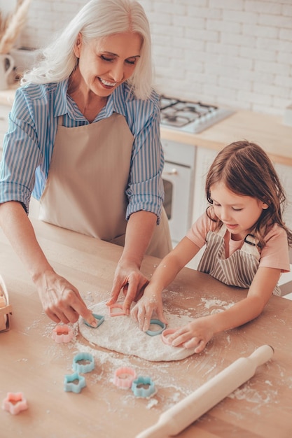 Draufsicht auf Großmutter und Enkelin, die Keksausstecher für die Zubereitung von Keksen auf dem Küchentisch verwenden