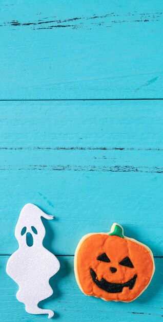 Draufsicht auf Halloween festlich dekorierte gebackene Zuckerguss-Lebkuchen-Zuckerplätzchen auf blauem Hintergrund mit Kopierraum und flacher Lage.