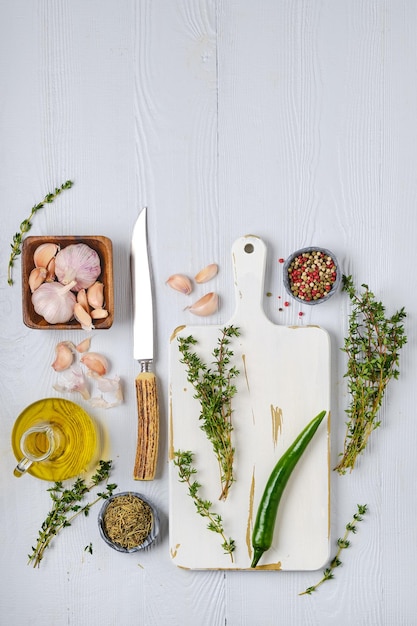 Draufsicht auf Holzschneidebrett mit frischem Thymian und Gewürzen für pikante Sauce oder Marinade