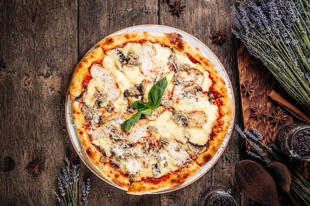 Draufsicht auf italienische frisch gebackene flauschige Teigpizza mit Pilzen auf dem Holztisch