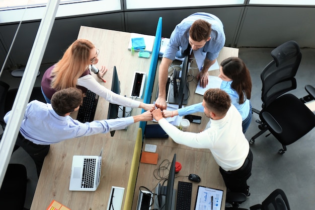 Draufsicht auf junge, moderne Kollegen in smarter Freizeitkleidung, die zusammenarbeiten, während sie Zeit im Büro verbringen.