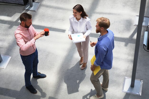 Draufsicht auf junge moderne Menschen in smarter Freizeitkleidung, die im Kreativbüro über das Geschäft diskutieren