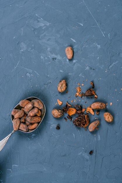 Draufsicht auf Kakaobohnen in Metalllöffel auf dunkler Tischplatte