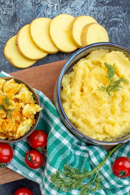 Foto draufsicht auf kartoffelpüree, serviert mit dill und leckerem gericht frischem gemüse auf grün gestreiftem handtuch auf holzbrett auf dunklem hintergrund mit freiem platz