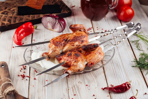 Draufsicht auf kaukasische gegrillte Hühnerspieße auf dem hellen Holztisch mit Saucen