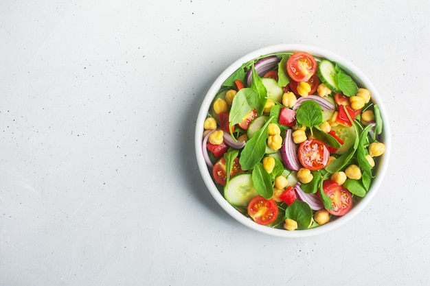 Draufsicht auf Kichererbsensalat zubereitet mit Tomaten, Gurken, roten Zwiebeln, Kressesalat und Rucola. Kichererbsen sind reich an Proteinen und Ballaststoffen. Platz kopieren