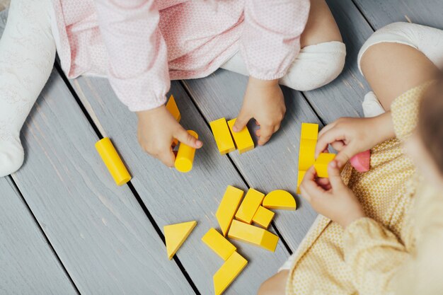 Draufsicht auf Kinderhände, die mit bunten gelben Blöcken spielen