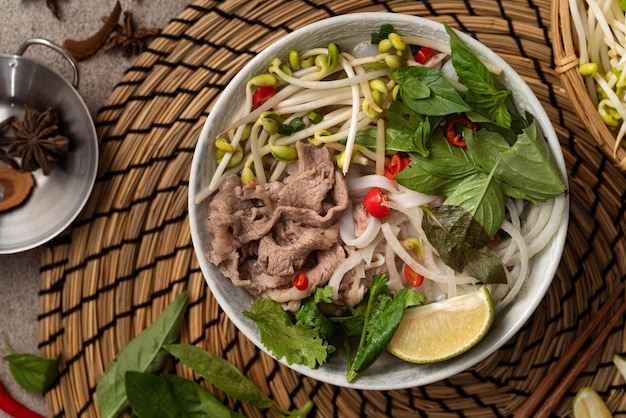 Draufsicht auf köstliche vietnamesische Rindfleischnudeln in einer Schüssel mit Zutaten mit Kopierraum.