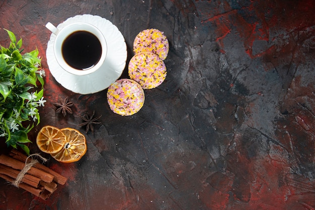 Draufsicht auf köstliche Zuckerkekse und eine Tasse Kaffeeblumentopf getrocknete Zitronen-Zimt-Scheiben auf dunklem Hintergrund