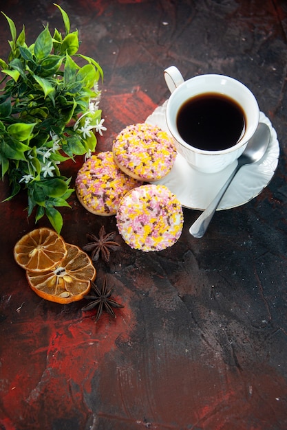 Draufsicht auf köstliche Zuckerkekse und eine Tasse Kaffeeblumentopf getrocknete Zitronenscheiben auf dunklem Hintergrund