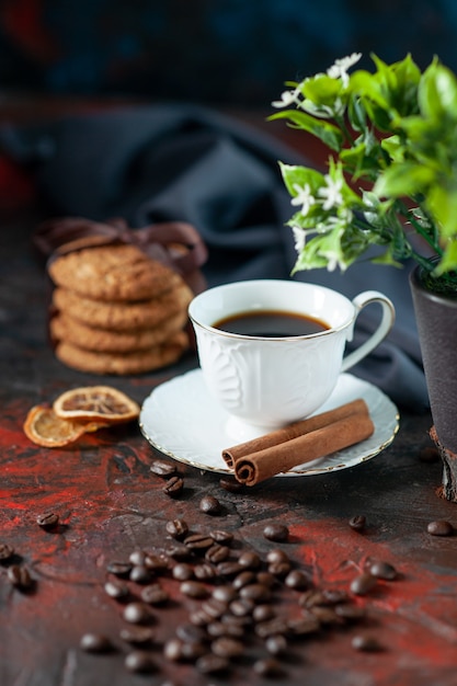 Draufsicht auf köstliche Zuckerkekse und eine Tasse Kaffeebohnen-Blumentopf-Zimt-Limonen-Handtuch auf dunklem Mischfarbenhintergrund