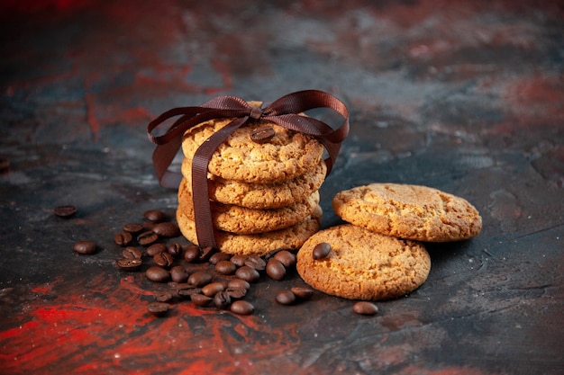 Draufsicht auf köstliche Zuckerkekse und Kaffeebohnen auf dunklem Hintergrund mit Mischfarben