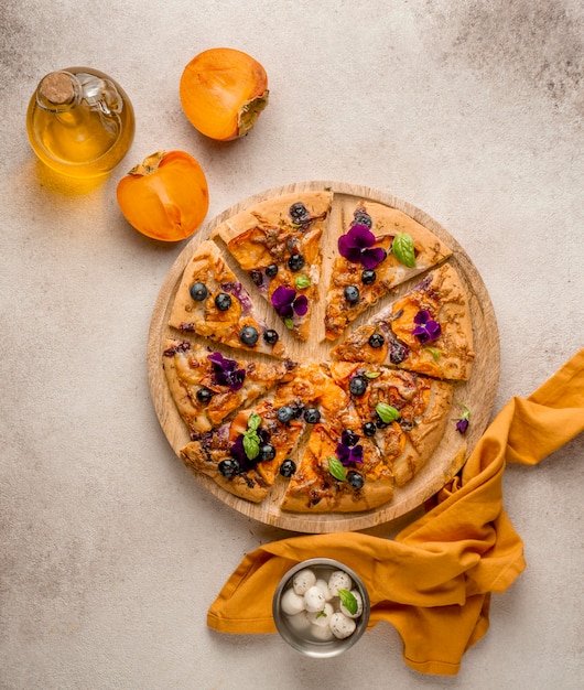 Draufsicht auf köstliches Stück Pizza mit Blütenblättern und Kakis