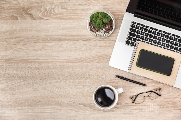 Draufsicht auf Laptop, Tasse Kaffee, Smartphone auf dem Bürotisch und freier Platz zum Einfügen