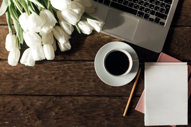 Draufsicht auf Laptops und Tulpen auf einem hölzernen Hintergrund