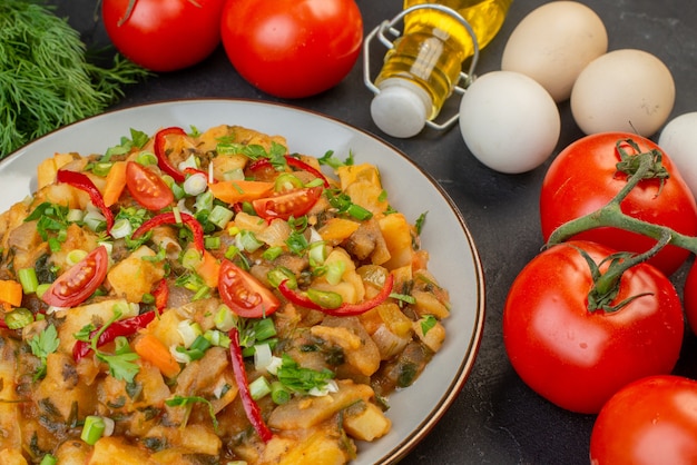 Draufsicht auf leckere vegane Mahlzeit frische Tomaten mit Stieleier gefallene Ölflasche auf schwarzem Hintergrund