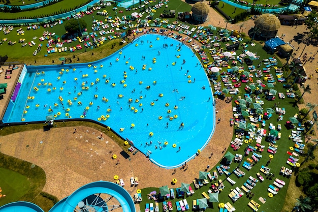 Draufsicht auf Leute, die sich im Pool auf gelben aufblasbaren Kreisen und Sonnenliegen am Strand entspannen.
