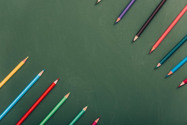 Draufsicht auf mehrfarbige Bleistifte auf grüner Tafel