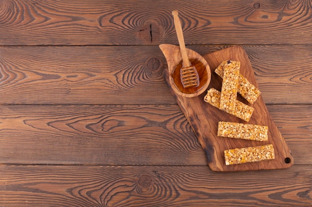 Draufsicht auf Müsliriegel mit Nüssen und Honig auf einem Holztisch, gesunder süßer Dessertsnack