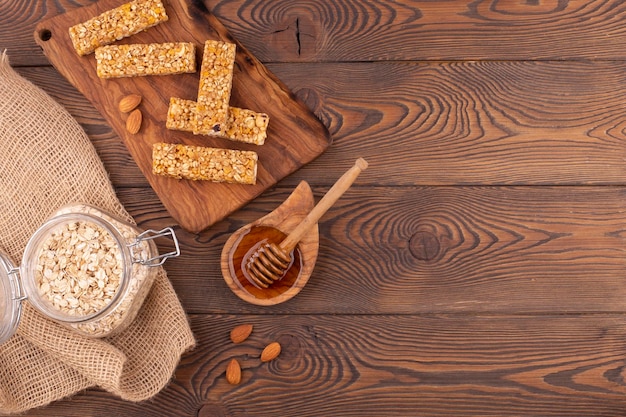 Draufsicht auf Müsliriegel mit Nüssen und Honig auf einem Holztisch, gesunder süßer Dessertsnack