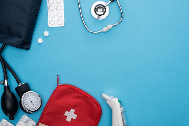 Draufsicht auf Ohrthermometer-Pillen in Blisterpackungen Erste-Hilfe-Kasten für Blutdruckmessgerät und Stethoskop