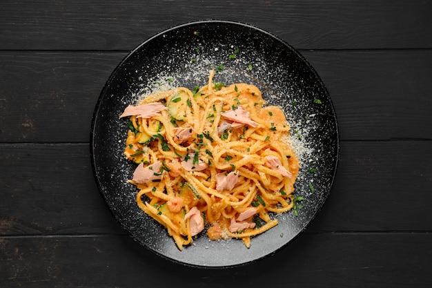 Draufsicht auf Pasta mit Lachs und Zuccini mit geriebenem Parmesan auf einem Teller