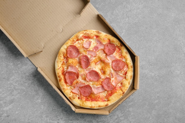 Draufsicht auf Pizza mit Wurst und Schweineschinken im Karton