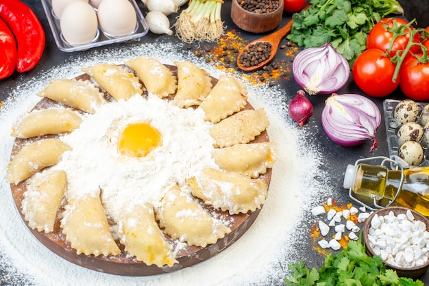 Draufsicht auf rohe Knödel auf Holztablett um Mehl und Lebensmittel