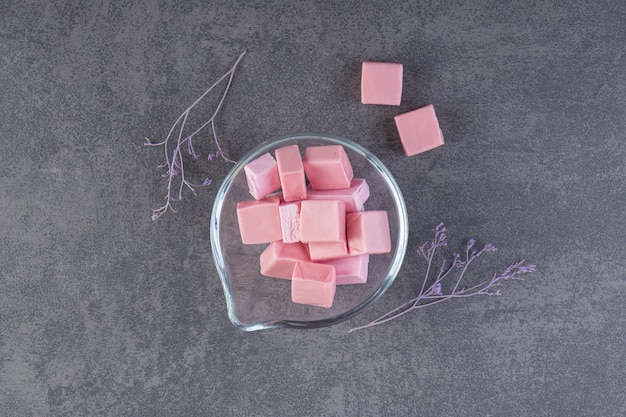 Draufsicht auf rosa Zahnfleisch in Glasschüssel über grauer Oberfläche.