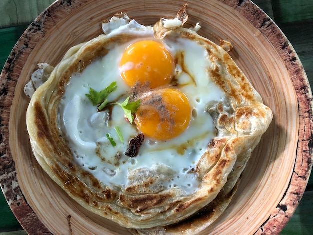 Draufsicht auf Roti Sarang Burung Es ist Pratha, das wie ein Vogelnest mit halb gekochten Eiern in der Mitte aussieht